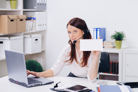 attractive woman with headset working in customer suppert holding blank signboard