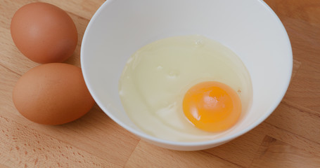 Breaking egg in glass bowl