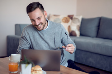 Man sitting on floor while watching laptop at home
