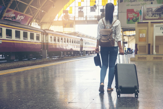 At train station,Young Tourist Girl walking,Dragging luggage suitcase and searching right direction.Asian Backpacker waiting train and planning happy holiday vacation.Travel concept.