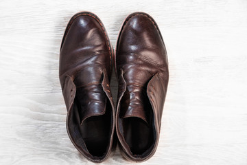 Autumn stylish man's boots on a white wooden background, top view