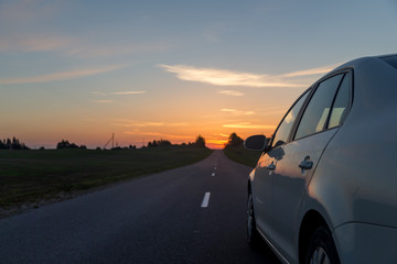 Fototapeta na wymiar Car driving towards the sunrise