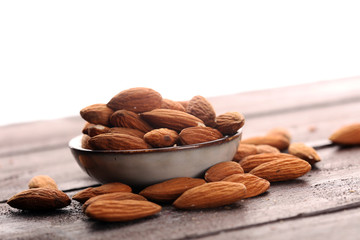 Almonds on a rustic wooden table and almond in bowl.