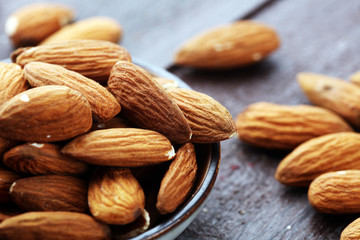 Almonds on a rustic wooden table and almond in bowl.