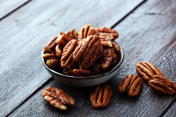 Pecan nuts on a rustic wooden table and pecan nuts in bowl