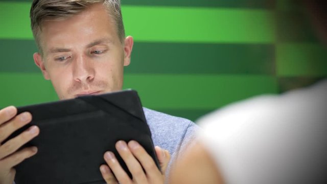 Close up young man looks at the tablet and nods his head in agree