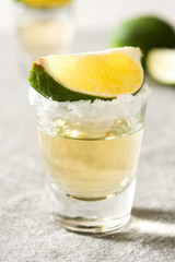 Mexican Gold tequila with lime and salt on gray background