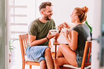 Young couple eating cereal breakfast at dining room table