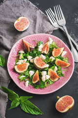 Fresh figs, cheese and greens. Healthy vegetarian salad on a concrete background.Overhead, top view, flat lay.