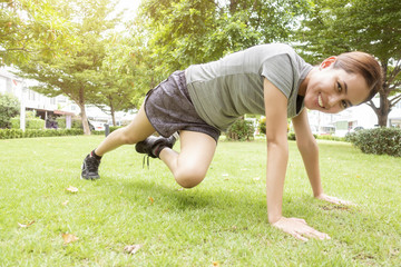 Beautiful sporty woman is doing exercises in green park