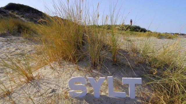 Sylt D&uuml;nen Landschaft mit Strandhafer  mit Sylt Buchstaben Leuchtturm H&ouml;rnum im Hintergrund