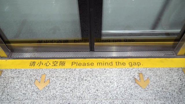 Shanghai subway door gap with people boarding. Mind the gap on metro, with doors opening, people getting off and getting on, looking down at hazardous space with commuters feet and shoes.