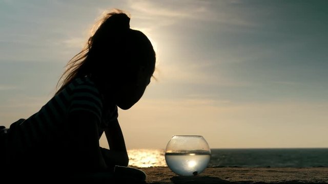summer season rest lying seashore small girl looking aquarium with a little fish . reflection water