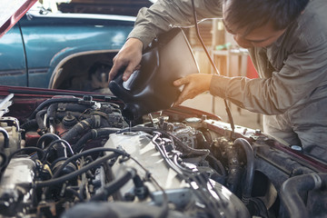 The car repairer is checking the car for maintenance. People who work on cars in the garage do...