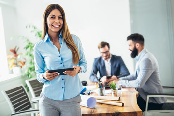 Portrait of young businesswoman using digital tablet while colleague in background