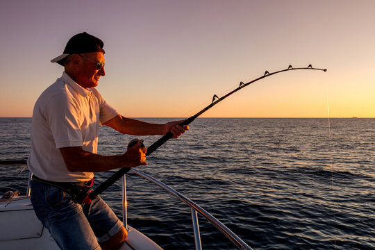 angler fishing on the sea from the boat at sunset