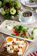 Italian Caprese salad and Cheese plate.. burrata cheese, tomatoes and basil herb leaves. Balsamic vinegar arranged on white plate
