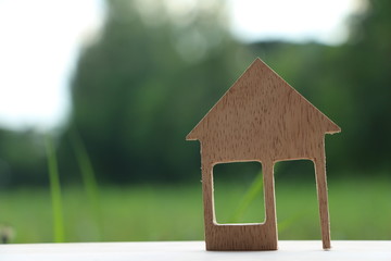 miniature wood house on green background with sunlight.Dream home with nature,mini icon.