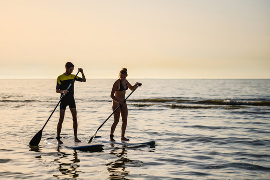 jeune couple de surfeur au coucher du soleil