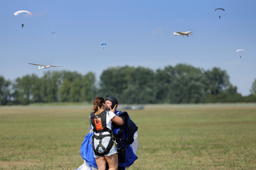 Para młodych ludzi w radosnym pocałunku po udanym skoku na spadochronie. - obrazy, fototapety, plakaty