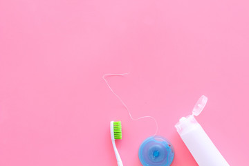 Set for daily teeth care. Toothbrush, tooth paste, dental floss on pink background top view copy space