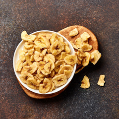 Dried banana slices on brown background. Top view of banana crunchies.