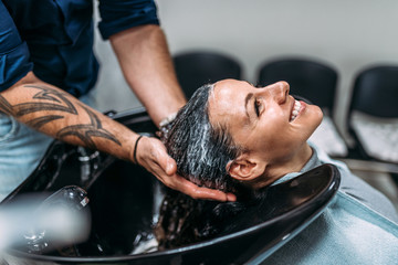 Smiling woman getting a hairwash or a hair treatment by a hairdresser.