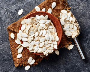 Raw pumpkin seeds on black background. Top view.
