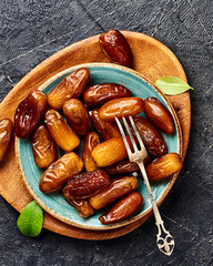 Dried dates fruits on plate. Top view of pitted dates.