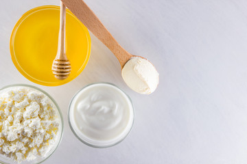 Milk products and honey with wooden cutlery. Cottage cheese, sour cream, cream on a white background top view. Different natural products for vegan. Healthy food