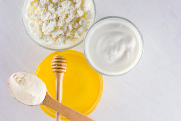 Milk products and honey with wooden cutlery. Cottage cheese, sour cream, cream on a white background top view. Different natural products for vegan. Healthy food