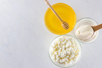 Milk products and honey with wooden cutlery. Cottage cheese, sour cream, cream on a white background top view. Different natural products for vegan. Healthy food