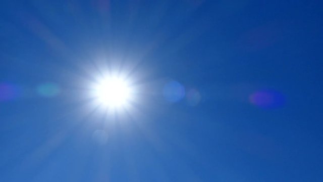 Bright scorching sun against the blue sky. A hot, sunny day. The sun is at its zenith.