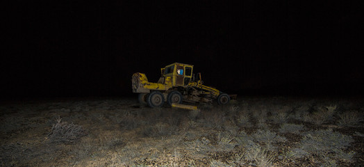 grader in the field at sunset