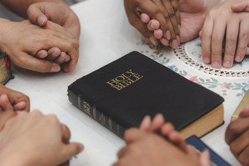 Christian worship praying to the holy scripture. they pray hands Bible in church for the faith and...