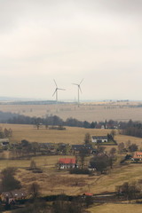 Pair of white wind turbines power station on border between Germany and Czech Republic near Petrovice in Ore Mountains, Krusne Hory, cloudy foggy winter day