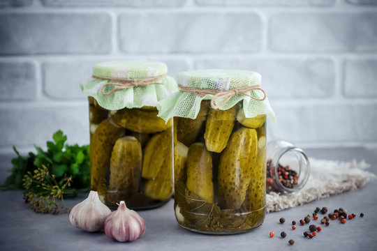 Pickled cucumbers  in glass jar on gray  table.