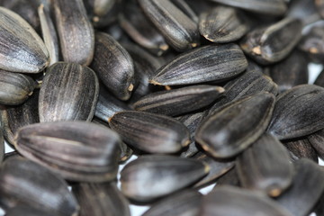 Black sunflower seeds. For texture or background. Seed sunflower. Collection of black sunflower seeds isolated on white. Pile of black sunflower seeds. Roasted seeds. Close-up of delicious sunflowers.