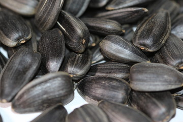 Black sunflower seeds. For texture or background. Seed sunflower. Collection of black sunflower seeds isolated on white. Pile of black sunflower seeds. Roasted seeds. Close-up of delicious sunflowers.