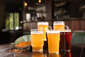Glasses of tasty beer on wooden table in bar