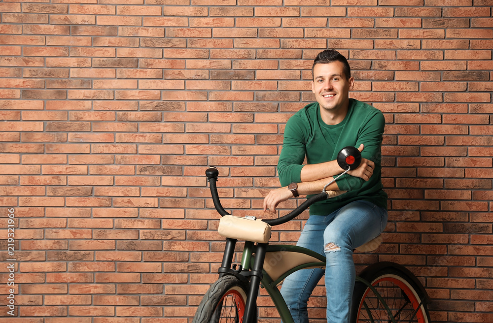 Sticker Portrait of handsome young man with bicycle near brick wall