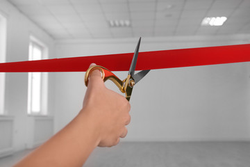 Woman cutting red ribbon on blurred background. Festive ceremony