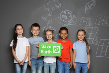 Little school children with placard SAVE EARTH and drawings on grey background