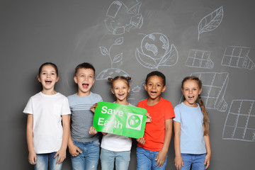 Little school children with placard SAVE EARTH and drawings on grey background