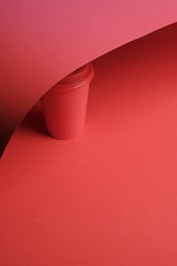 Red plastic coffee cup on a red background with a red lid