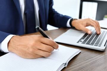 Lawyer working with laptop and notebook at table, closeup