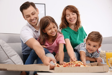 Family eating pizza while watching TV in room