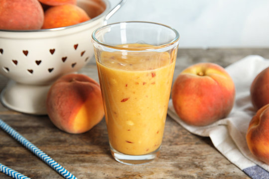 Tasty peach smoothie in glass on wooden table