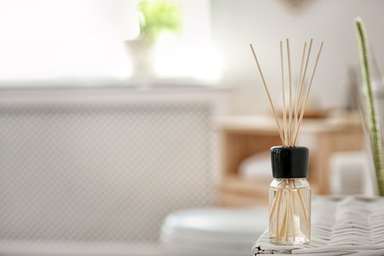 Aromatic reed air freshener on table against blurred background