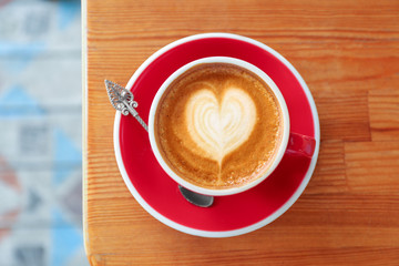 Cup of fresh aromatic coffee on wooden table, top view